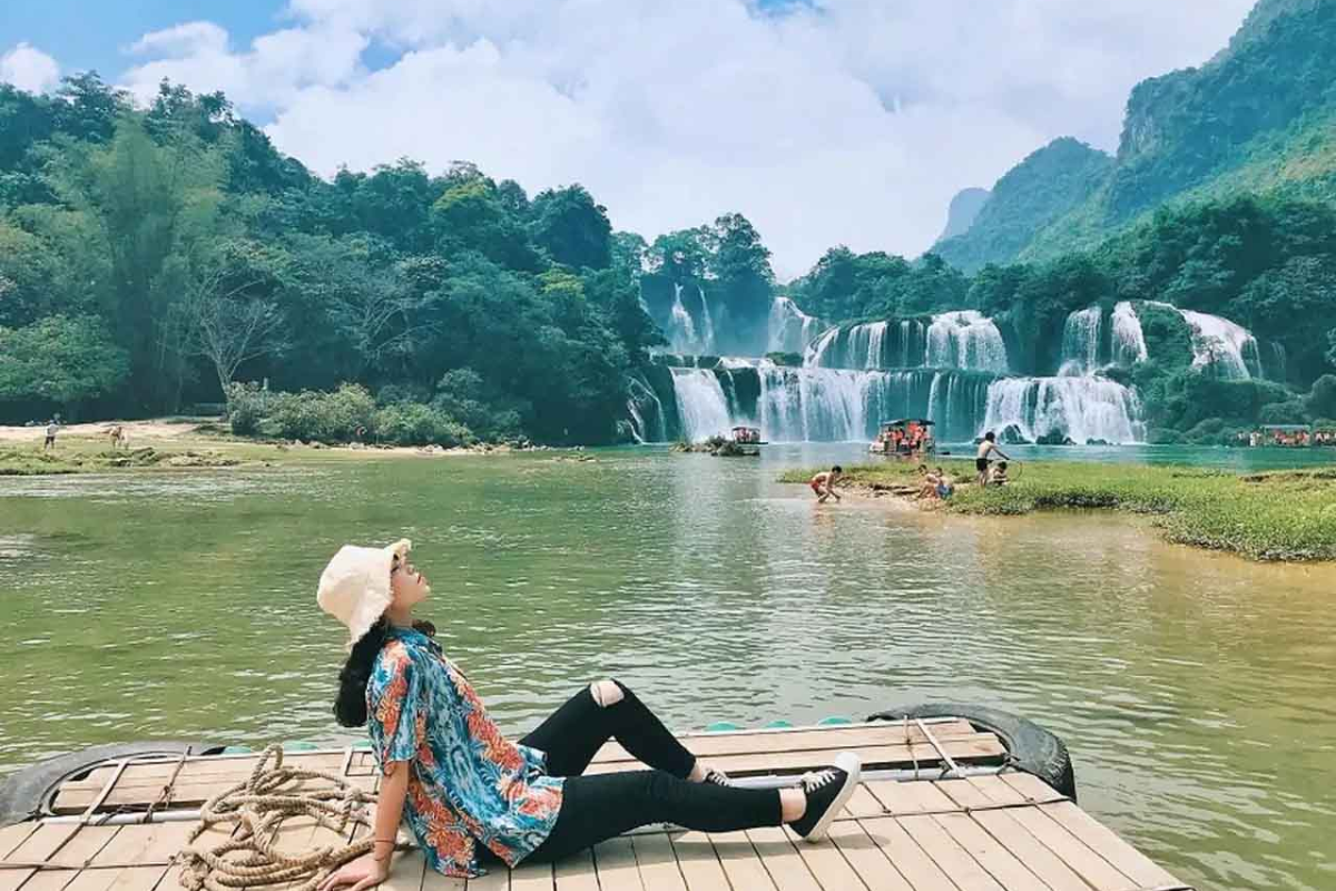 Traveler relaxing in a riverside hut with views of Ban Gioc Waterfall in July